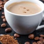 image of roasted coffee beans, ground coffee and a cup of hot coffee