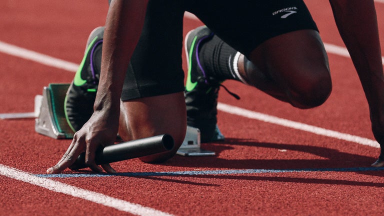 photo of a runner kneeling on track