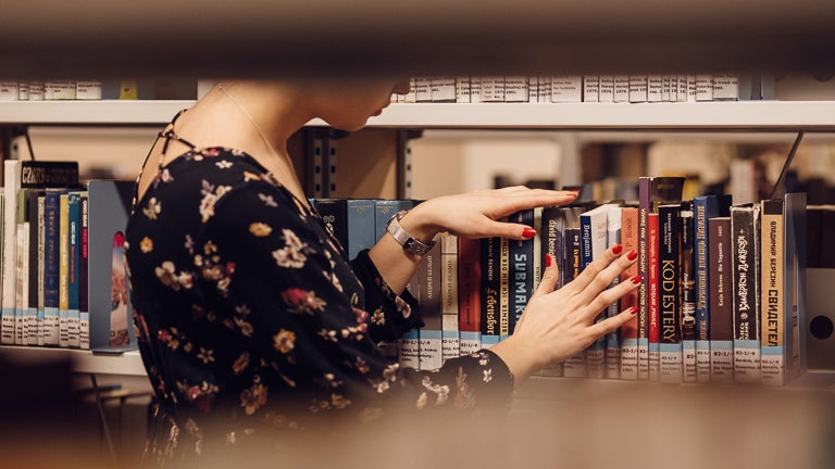 photo of librarian organizing books on library shelf