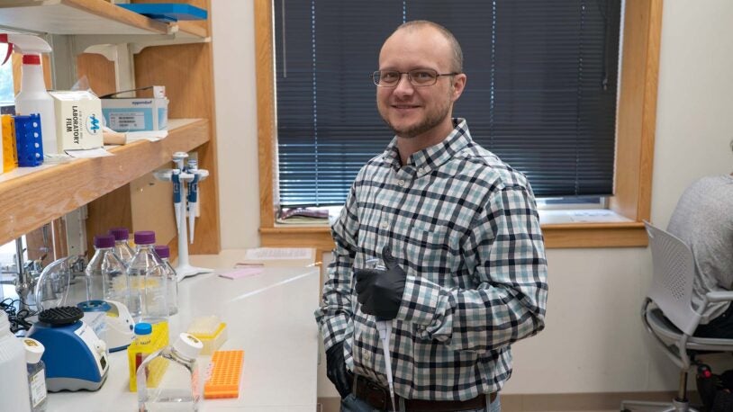 photo of Lucas Cheadle in a lab holding a pipette