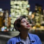 photo of woman looking at the city lights at night