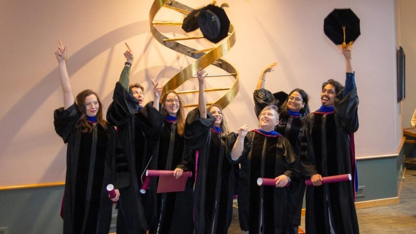 photo of SBS graduating students throwing their caps in the air