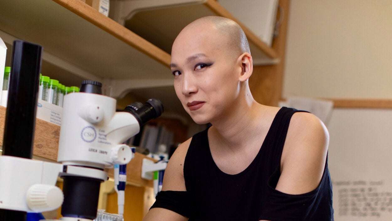 photo of Simone Sun working at a microscope in their lab