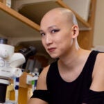photo of Simone Sun working at a microscope in their lab