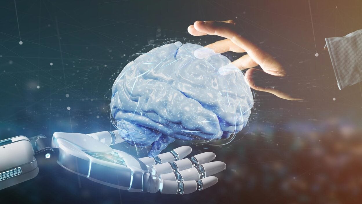 Image of human and robot hands holding AI brain