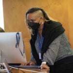 Solange Baptiste standing in the conference room during the May 2022 "Optimizing Effective Coverage of HIV/STI Prevention and Care Programs: A Program Science Approach" meeting.