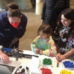 image of a DNALC faculty member showing 3 children the DNA sequencer