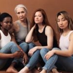 image of diverse women in casuals sitting on brown background. Multi-ethnic group of females looking at camera in studio.