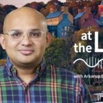 image of Cold Spring Harbor campus from across the harbor with At the Lab podcast logo and portrait of Arkarup Banerjee