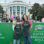 image of CSHL scientists Janeen Braynen and Audrey Fahey standing in front of the White House 2024 Easter EGGucation Roll sign in Washington DC