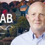 image of Cold Spring Harbor campus from across the harbor with At the Lab podcast logo and portrait of Rob Martienssen