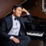 image of Abraham Alinea sitting at a grand piano