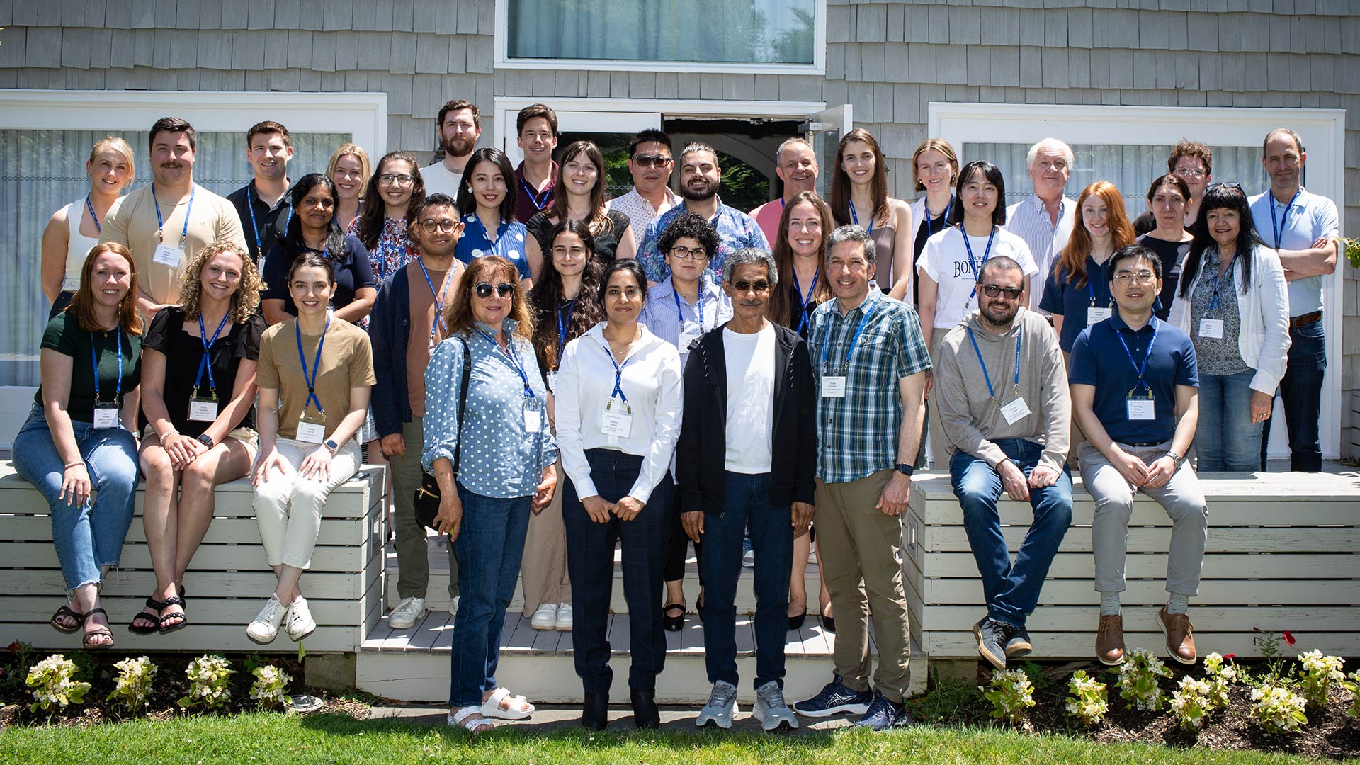 The 2024 brain tumor meeting poses for a photo on steps outside a building on a sunny day.