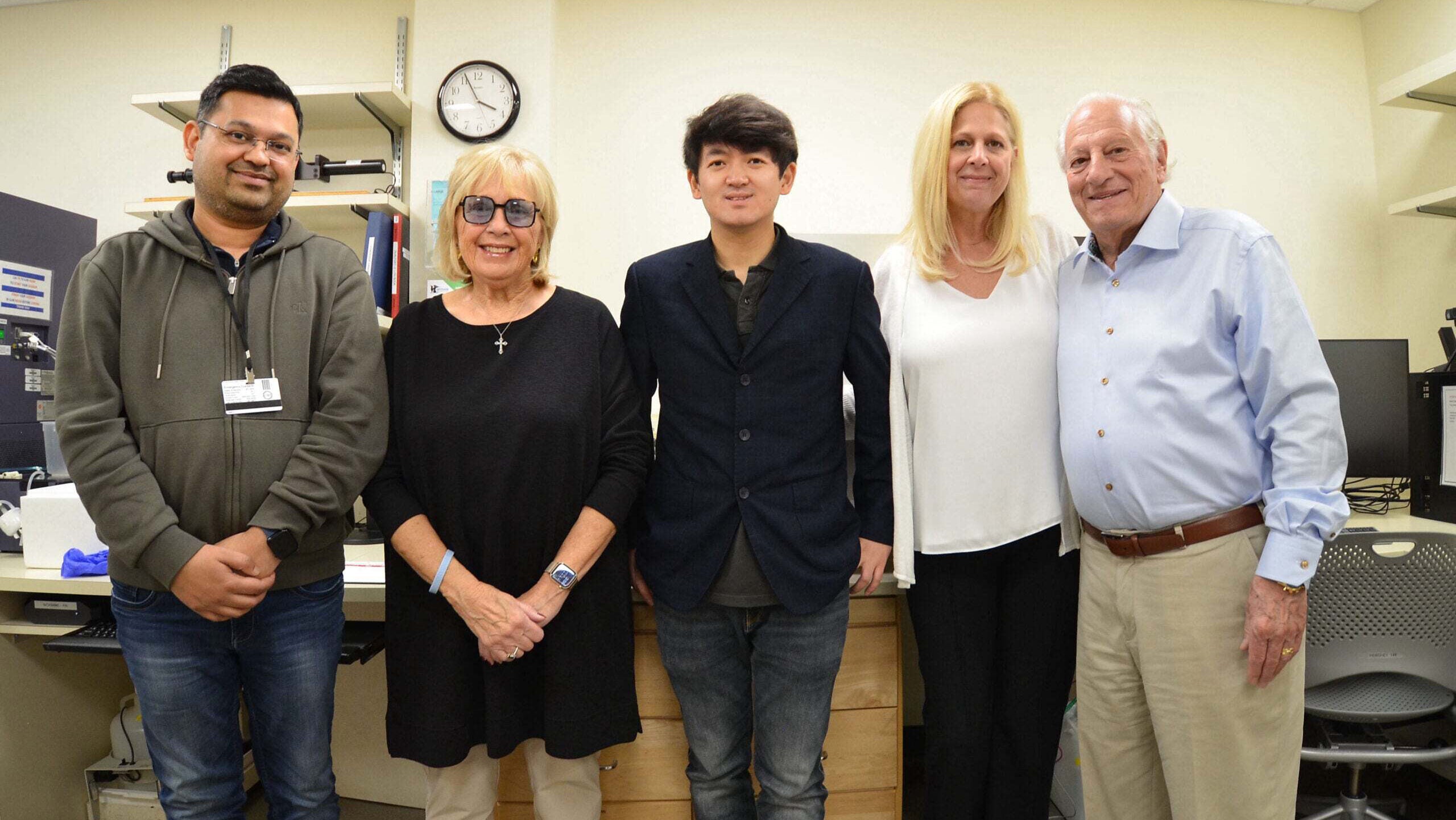 Dr. Lingbo Zhang (middle) with a member of his lab (far left) and the Saladino family from the Monti Foundation standing together in his lab.