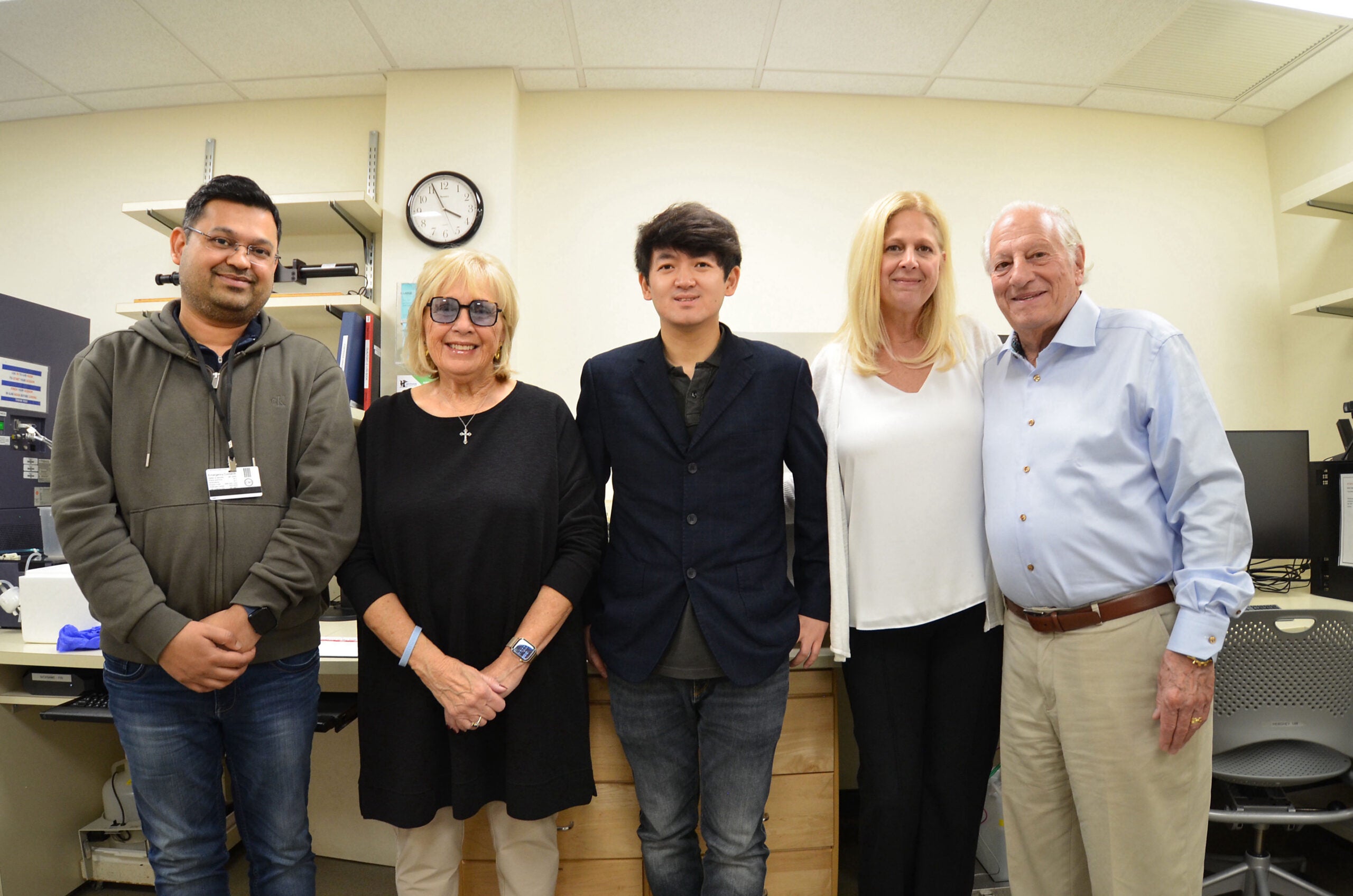 Dr. Lingbo Zhang (middle) with a member of his lab (far left) and the Saladino family from the Monti Foundation standing together in his lab.